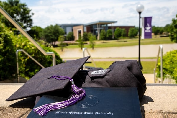 MGA cap and gown resting on the stairs of the Student Life Center on the Macon Campus.